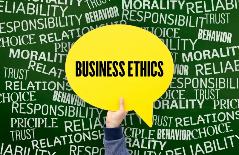 A hand holds up a yellow speech bubble that reads, "Business Ethics" while the background is full of ethics-related words.