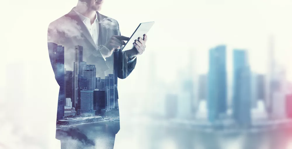 A market researcher studies a tablet with a city skyline in the background.