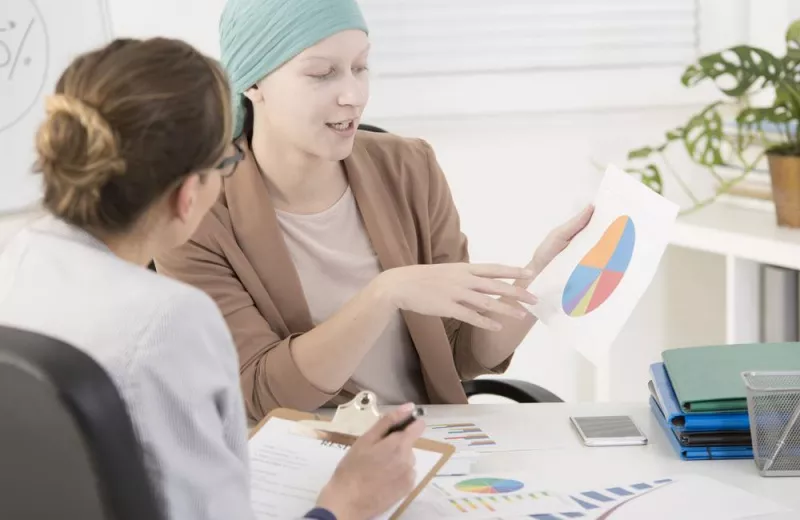 Cancer and Big Data statistics conveyed from doctor to patient in an office.